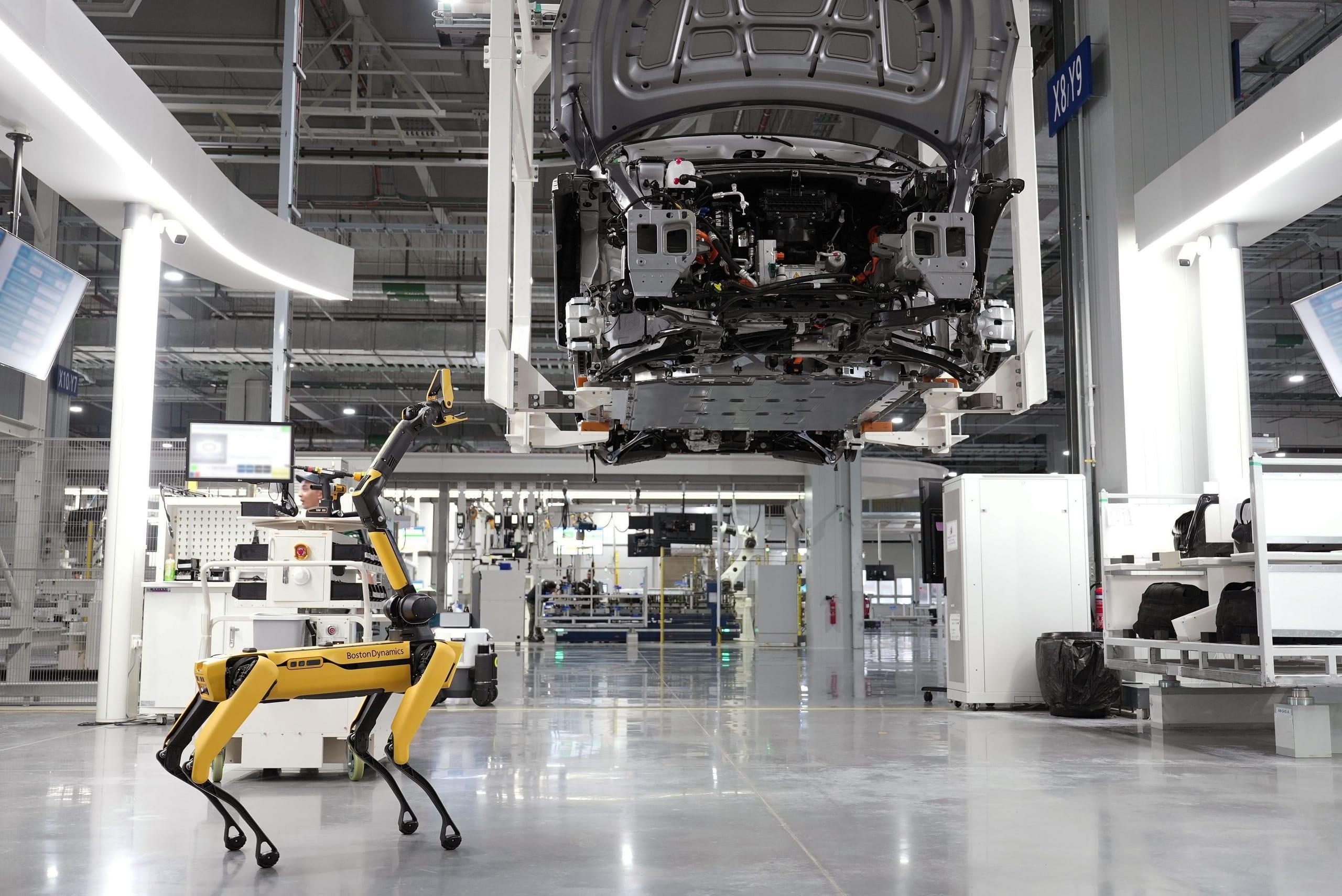 A humanoid factory robot standing on an automotive assembly line